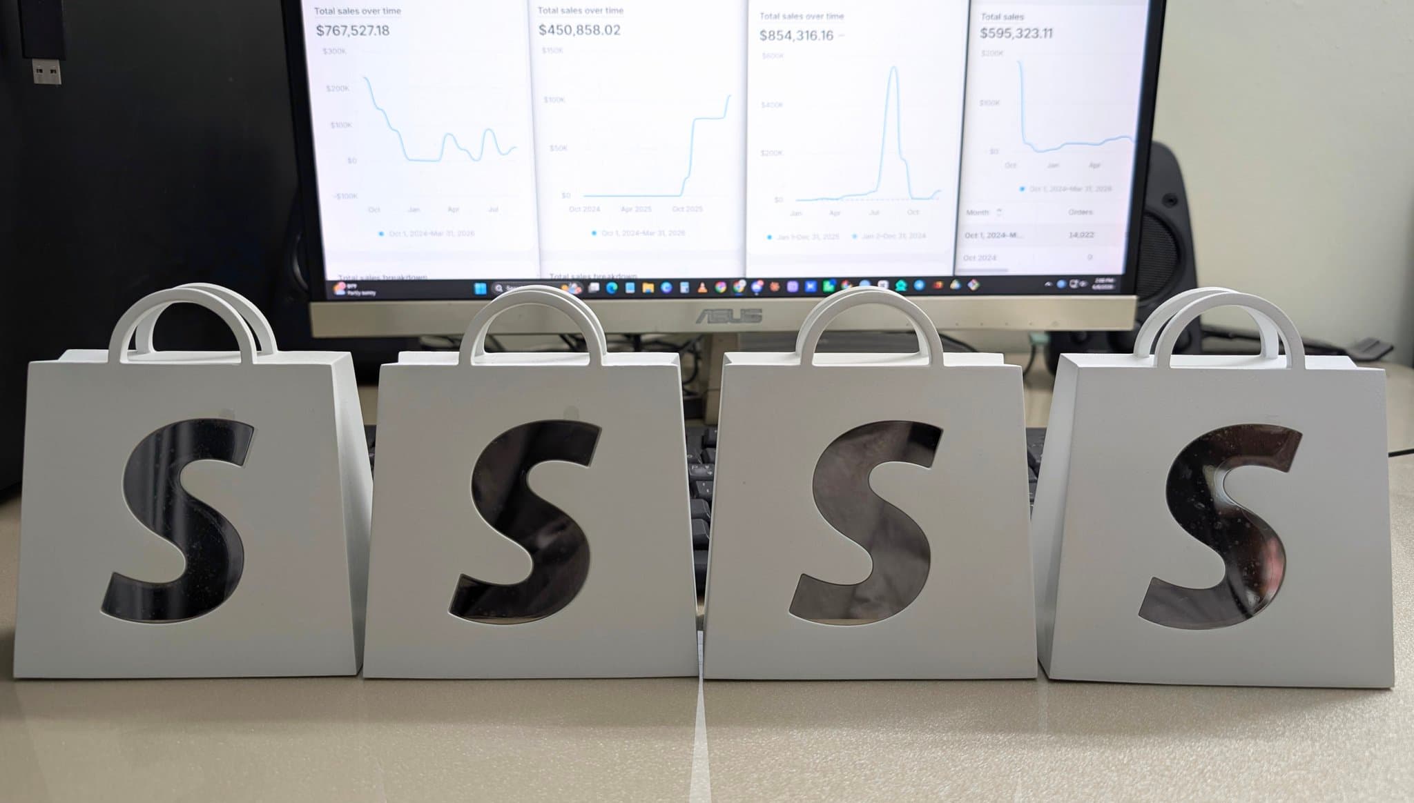 Four Shopify milestone awards in front of their store dashboards